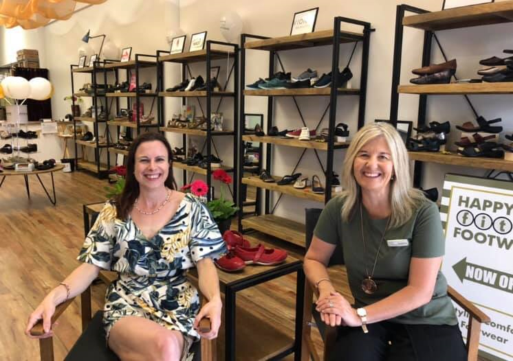 Ladies sitting on directors chairs in middle of a shoe shop