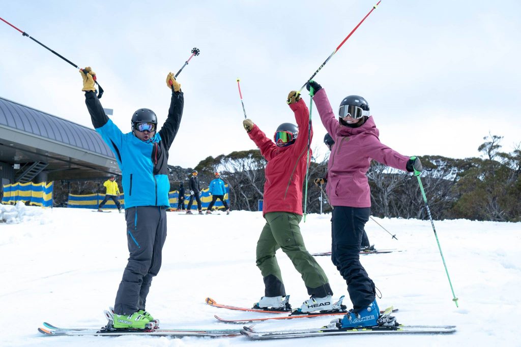 3 excited skiers waving their poles